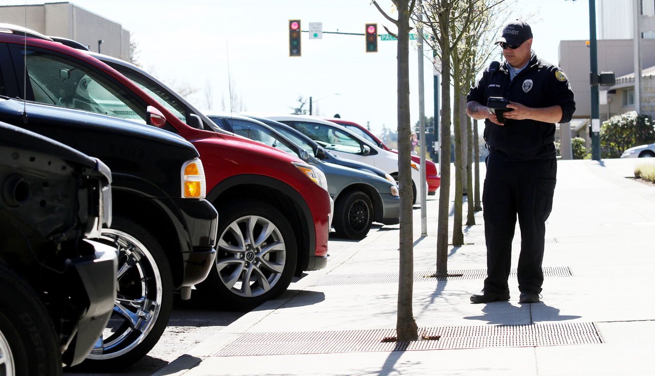 Everett Parking Enforcement Officer Miguel Betancourt enters license plate numbers into a handheld computer as he checks parked vehicles for violations Wednesday in Everett.