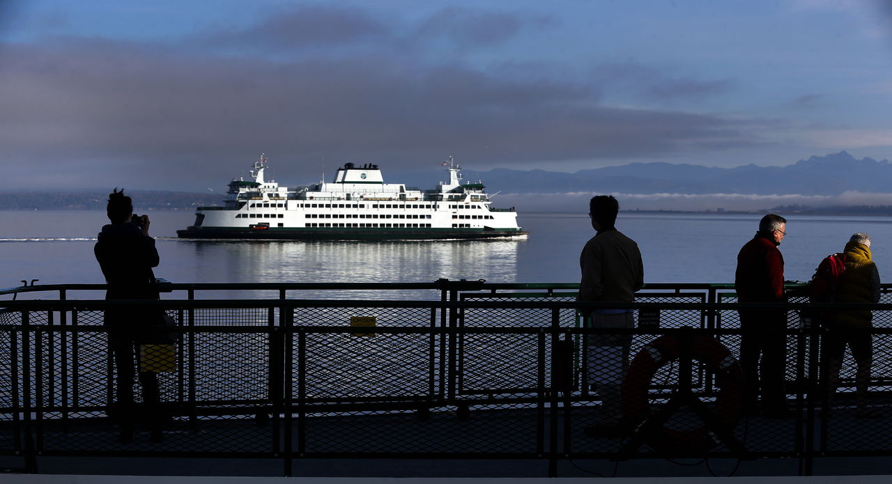 Passengers on the shady westbound end of the ferry from Mukilteo to Clinton on Whidbey Island watch and photograph the eastbound ferry, which gleams in the early morning sun. State ferries are popular with tourists.. “When you picture Snohomish County, that’s kind of the iconic image, the ferries with the mountains in the background,” Snohomish County Tourism director Amy Spain said.