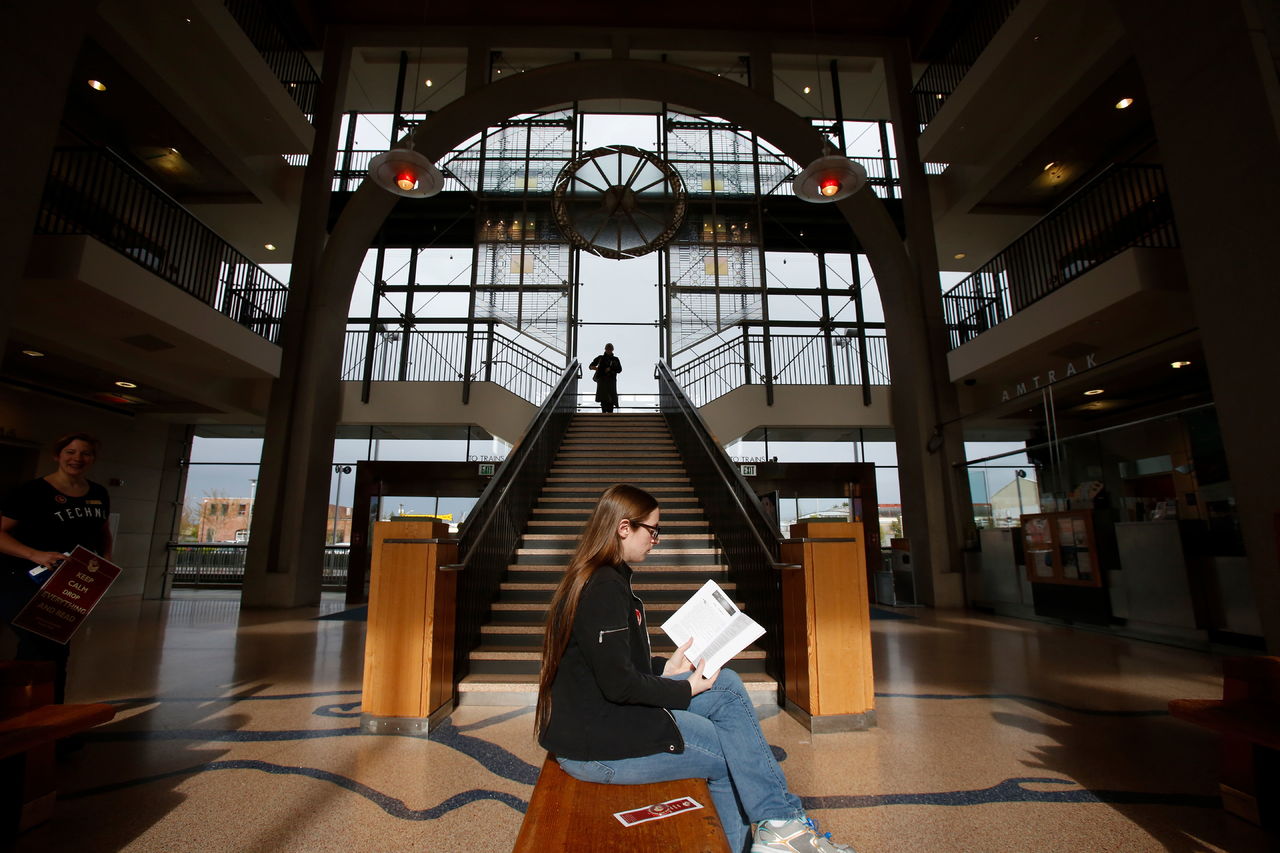 Sunlight pours through the Everett Transit Center as Jennifer Fulk reads “Dragon Flame” during an Everett Public Library flash mob event called “Drop Everything and Read” on Tuesday.