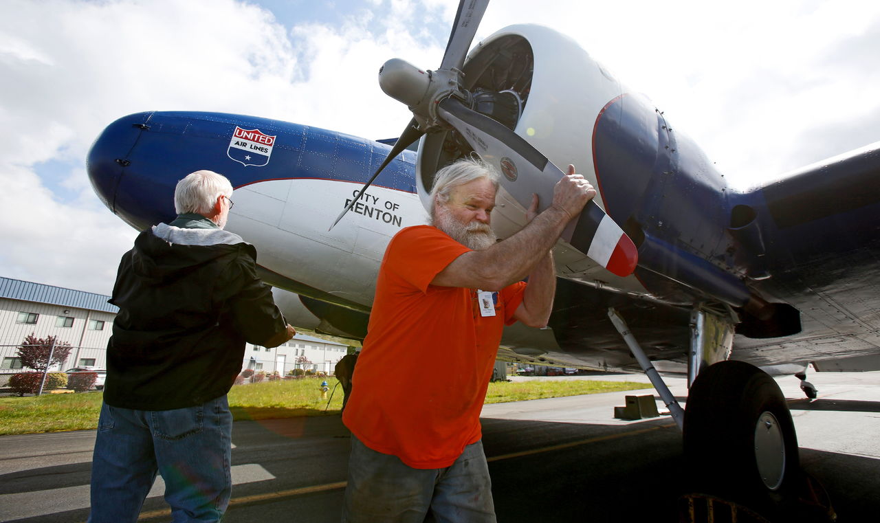 Dana Dillard (right) and Tom Locke take turns grabbing a propeller blade and rotating it to pump oil out from the bottom of the cylinders on each engine before the final flight of the Boeing 247 on Tuesday in Everett.