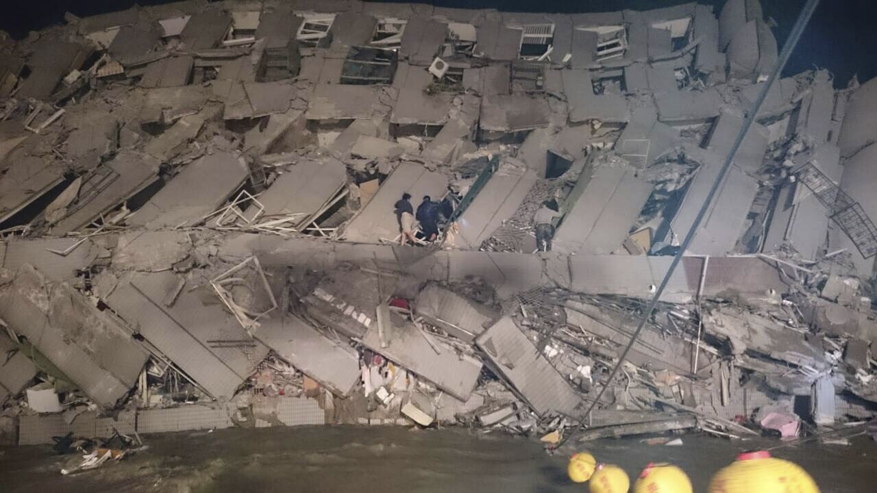 Rescuers enter an office building that fell on its side after an early morning earthquake in Tainan, Taiwan, on Saturday.