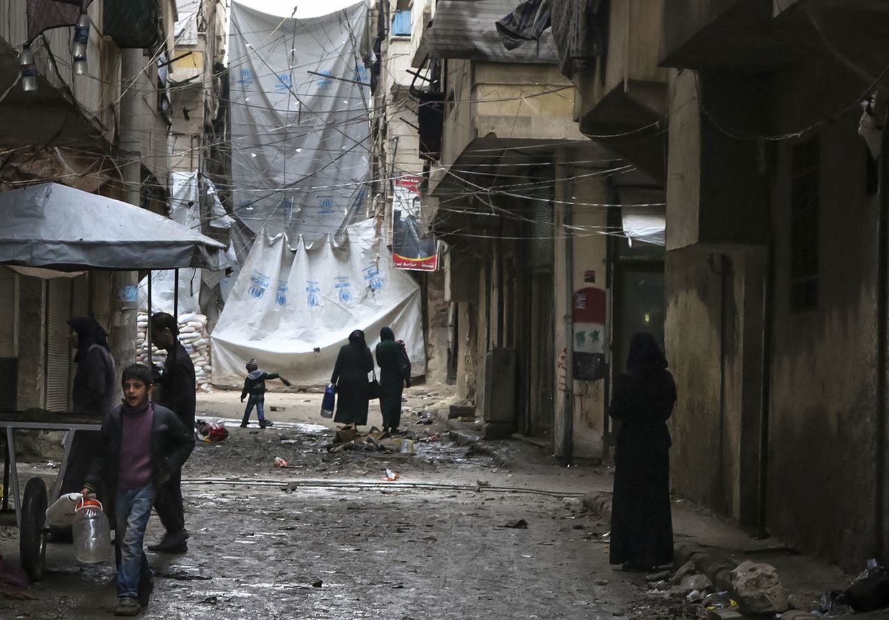 Civilians walk through a street with large tarps are hung in between building to limit the view of regime snipers in Aleppo, Syria, on Thursday. The fighting around Syria’s largest city of Aleppo has brought government forces closer to the Turkish border than at any point in recent years, routing rebels from key areas and creating a humanitarian disaster as tens of thousands of people flee.