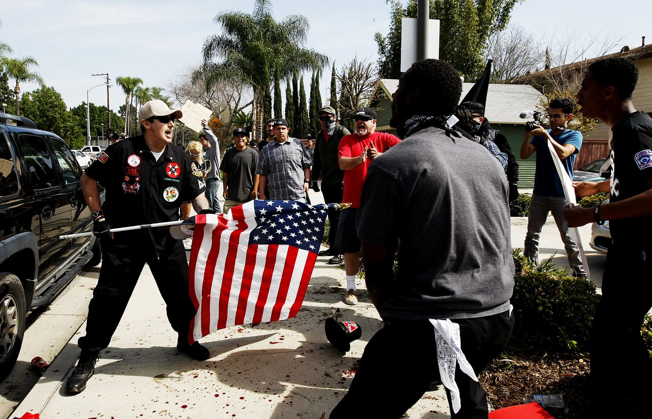 A Ku Klux Klansman uses an American flag to fend off angry counter protesters after members of the KKK tried to start a "White Lives Matter" rally in Anaheim, California, on Saturday.