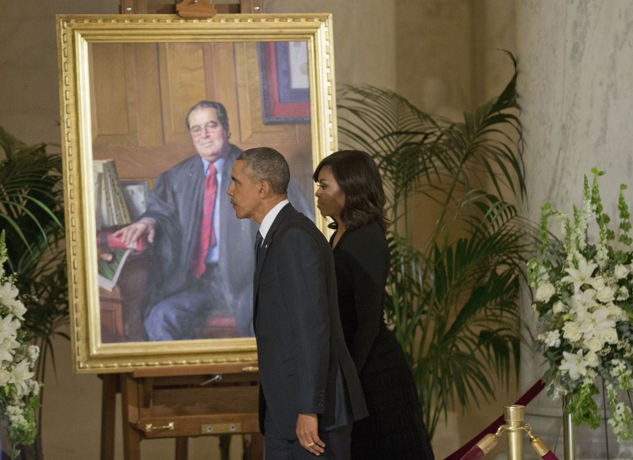 President Barack Obama and first lady Michelle Obama walk by a portrait of Supreme Court Justice Antonin Scalia after paying their respects at his casket in the Great Hall of the Supreme Court in Washington on Friday.