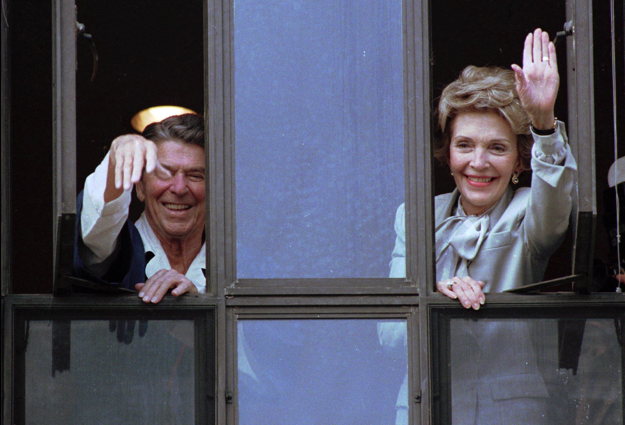 In this July 18, 1985, photo, President Ronald Reagan and his wife, Nancy, wave from windows of his hospital room at the Navy Medical Center in Bethesda, Maryland.