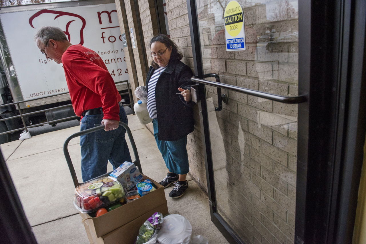 Rosalba Diaz holds the door for volunteer Dean Swanson on Thursday at the Manna Food Center in Gaithersburg, Maryland. As of Friday, food-stamp recipients in Maryland face a work mandate.