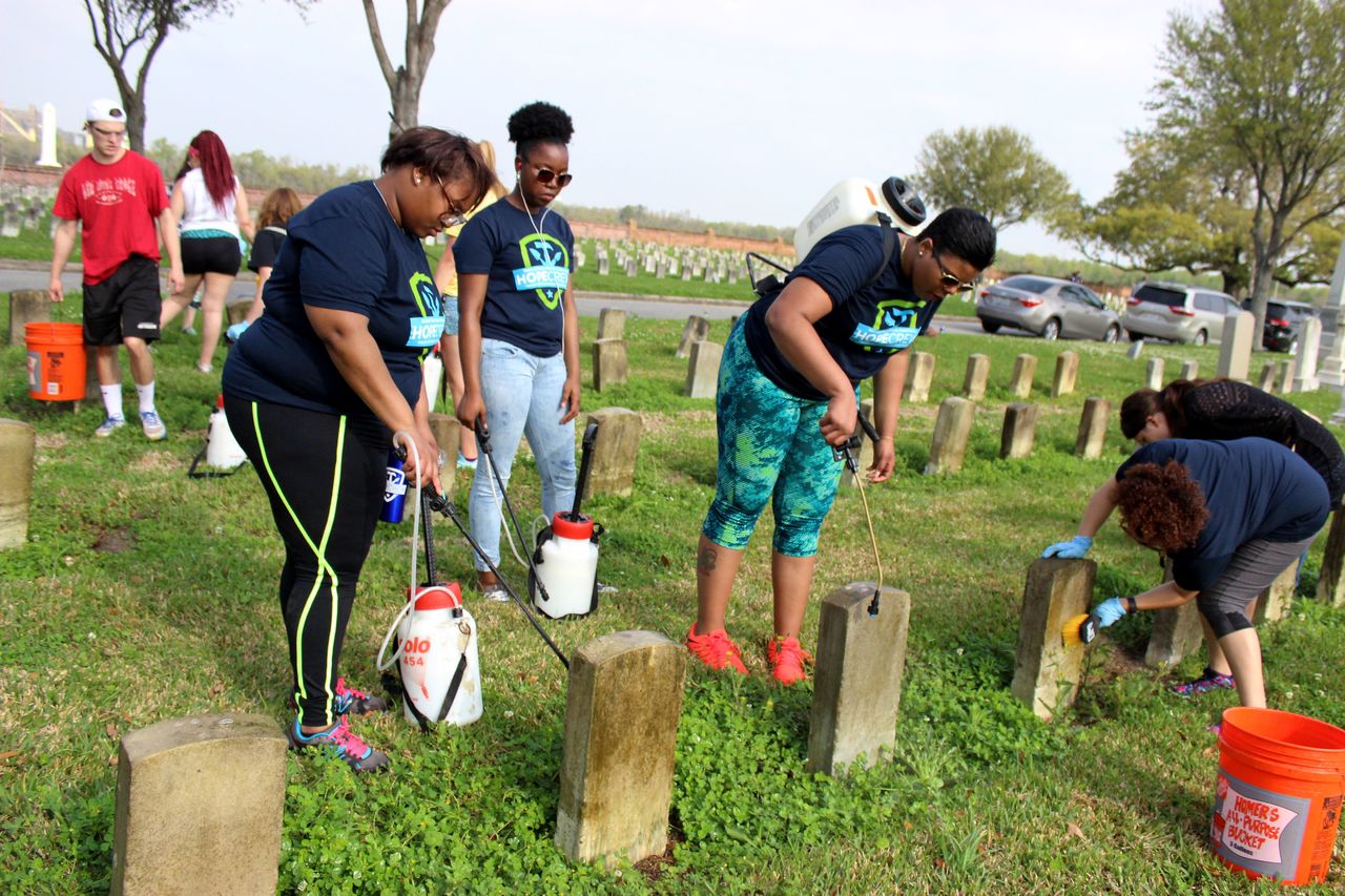 Ohio State University students Willie Love (left), of Cincinnati, and Ashauna Mathews, of Canton, Ohio, spray a cleaning solution on gravestones at Chalmette National Cemetery in Chalmette, Louisiana. Between them is Jasmine Harris, of Cleveland. They were among about 50 Ohio State students working at the cemetery, as part of a nearly month-long project organized by the National Trust for Historic Preservation.