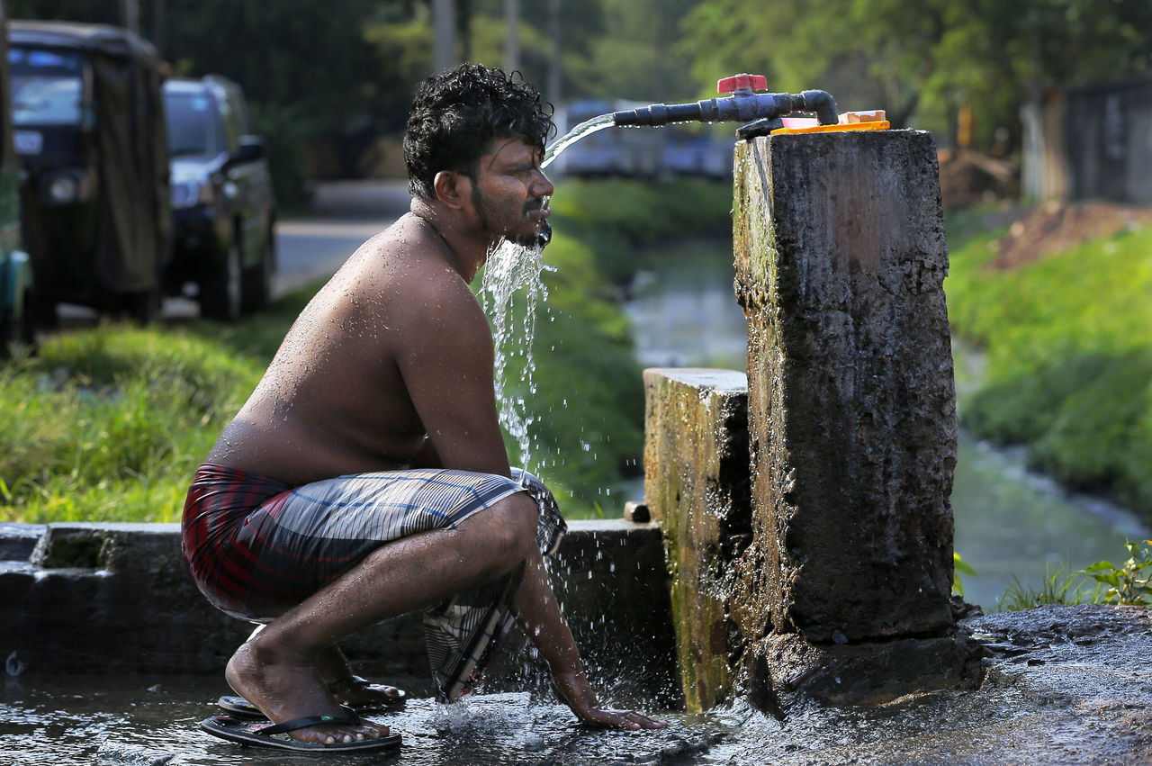 In this March 14 photo, a Sri Lankan man takes a bath from a roadside tap to cool himself off from the rising temperature in Colombo, Sri Lanka. Earth’s record heat streak has hit a record 11 months. The National Oceanic and Atmospheric Administration announced Tuesday that March’s average global temperature of 54.9 degrees was not only the hottest March, but continues a record streak that started last May.