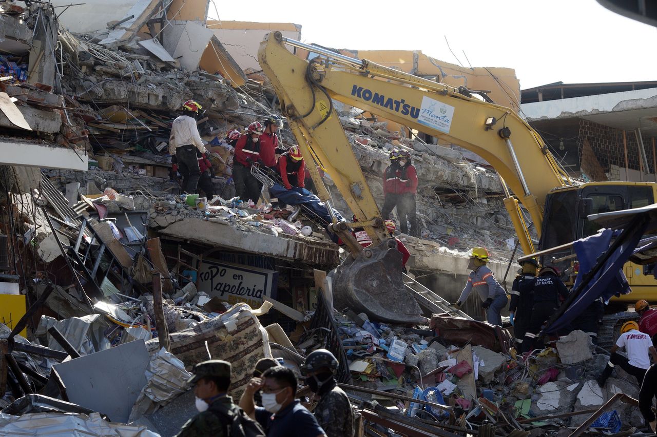 Rescue workers recover a body from the rubble Tuesday, as a bulldozer removes the debris of a collapsed building felled by the earthquake.