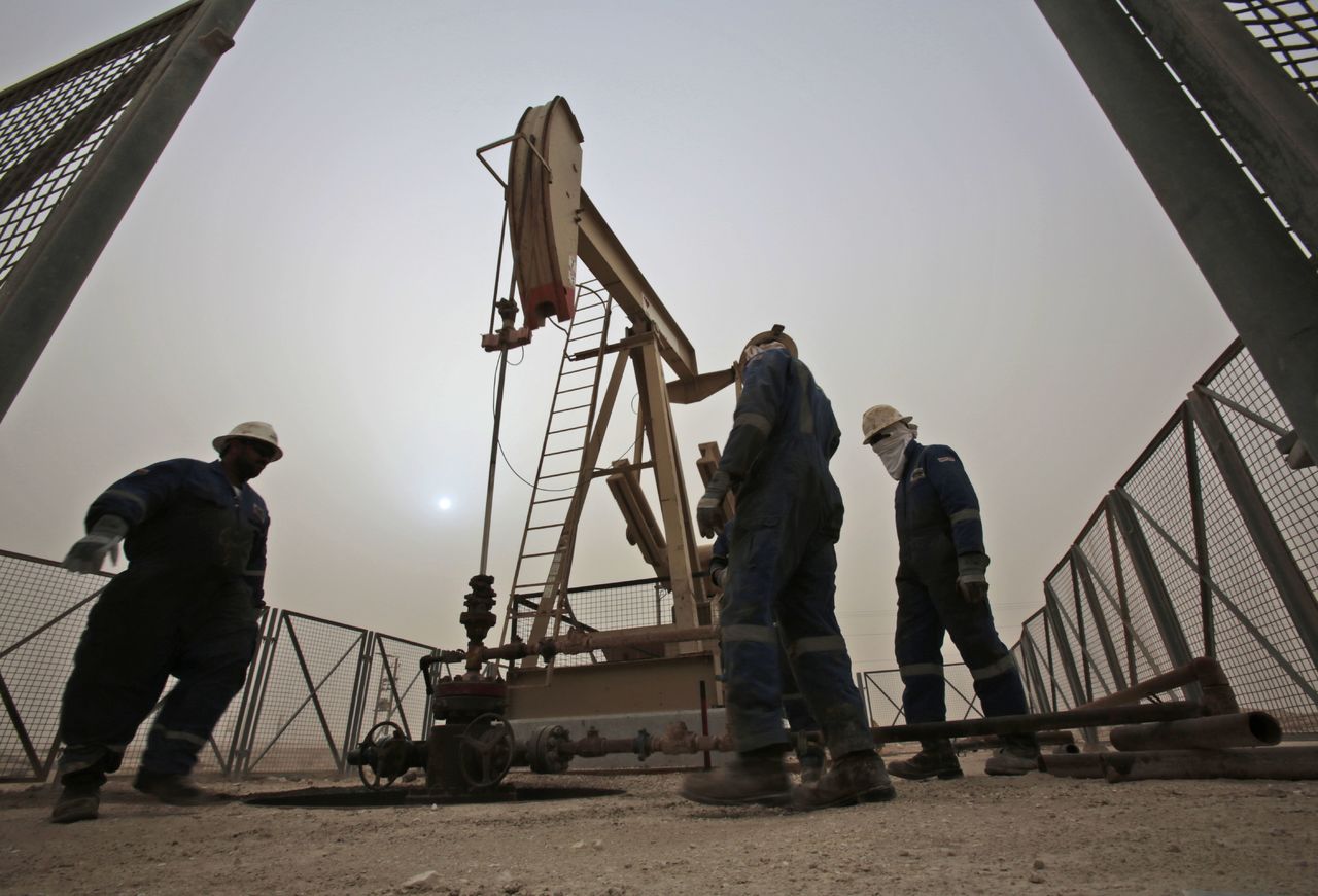 Men work on an oil pump during a sandstorm in the oil fields of Sakhir, Bahrain.