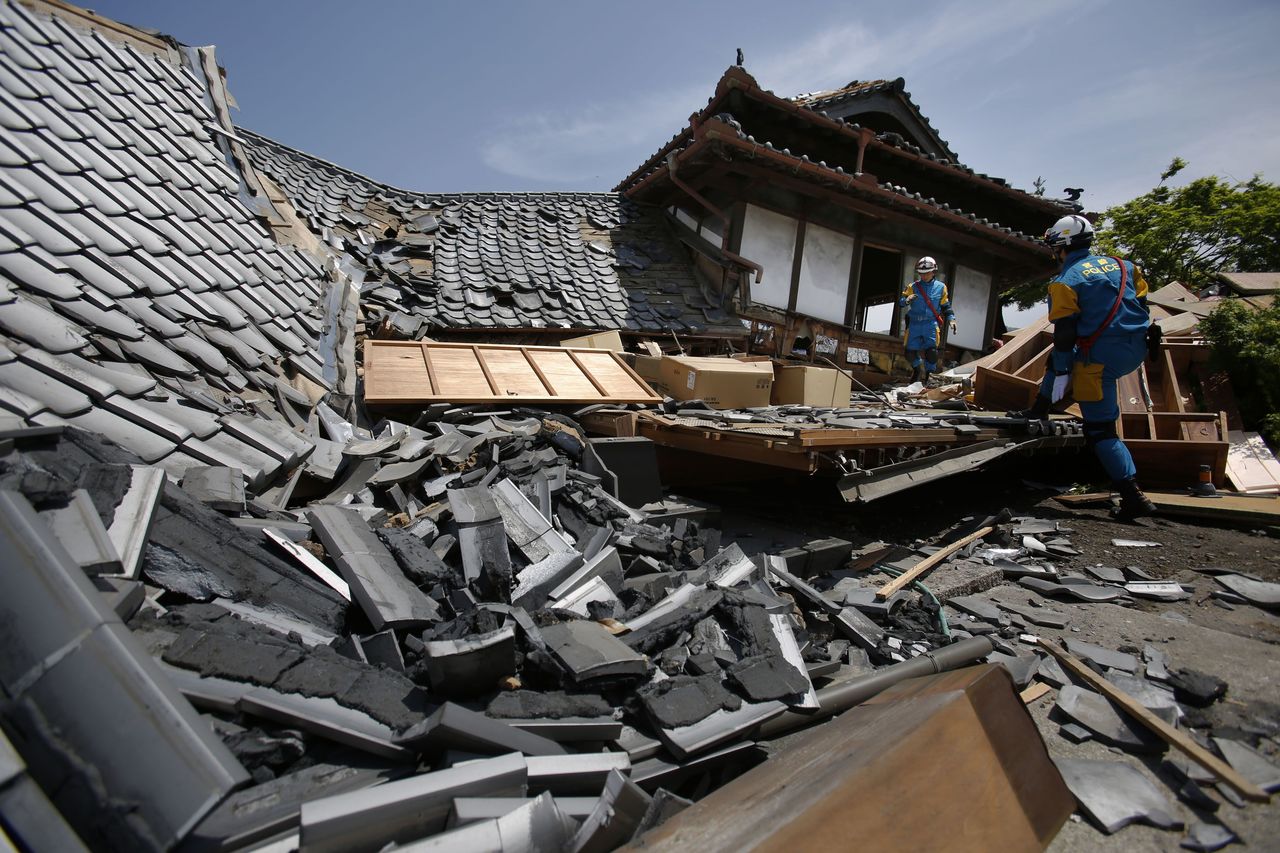 Police check for people trapped in collapsed houses in Mashiki on Friday.