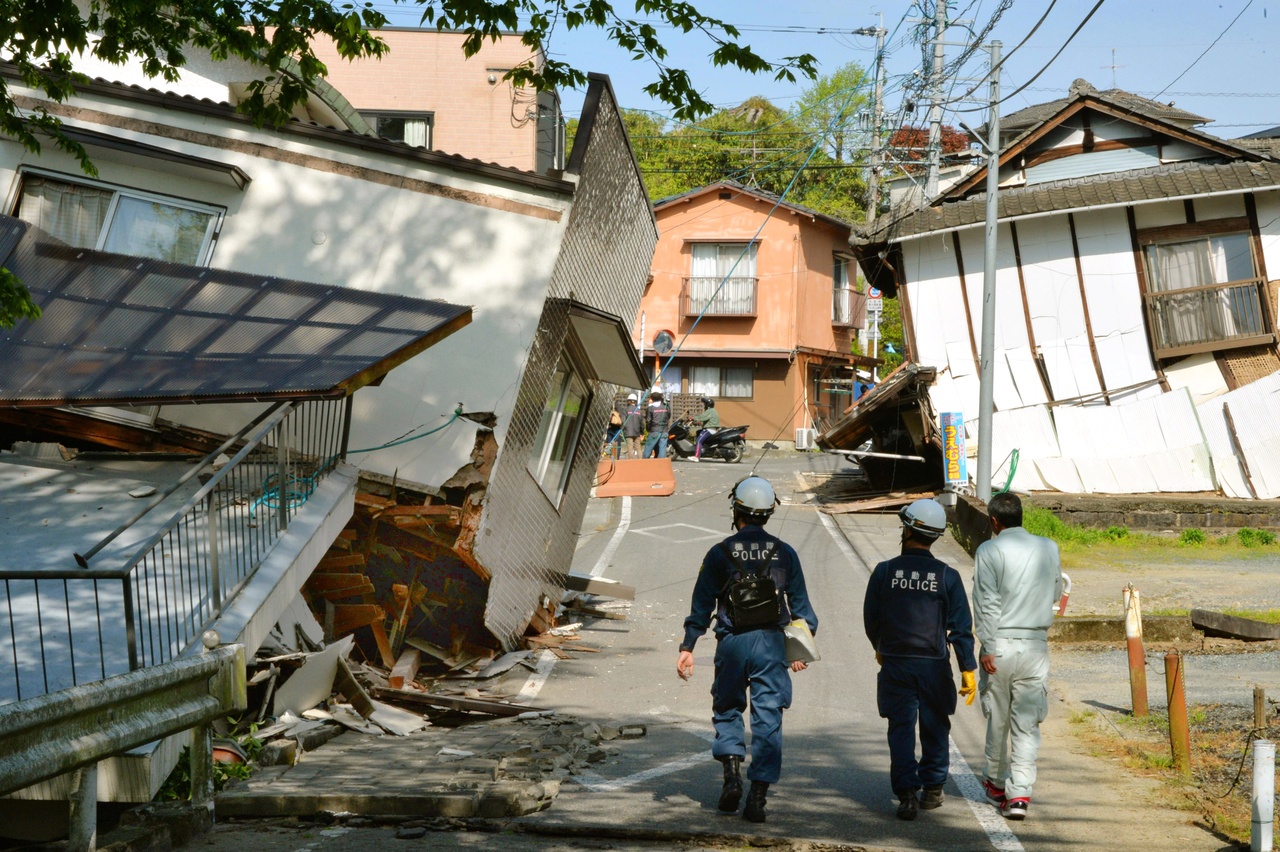 Police examine the damage to houses collapsed by a magnitude-6.5 earthquake in southern Japan on Friday.