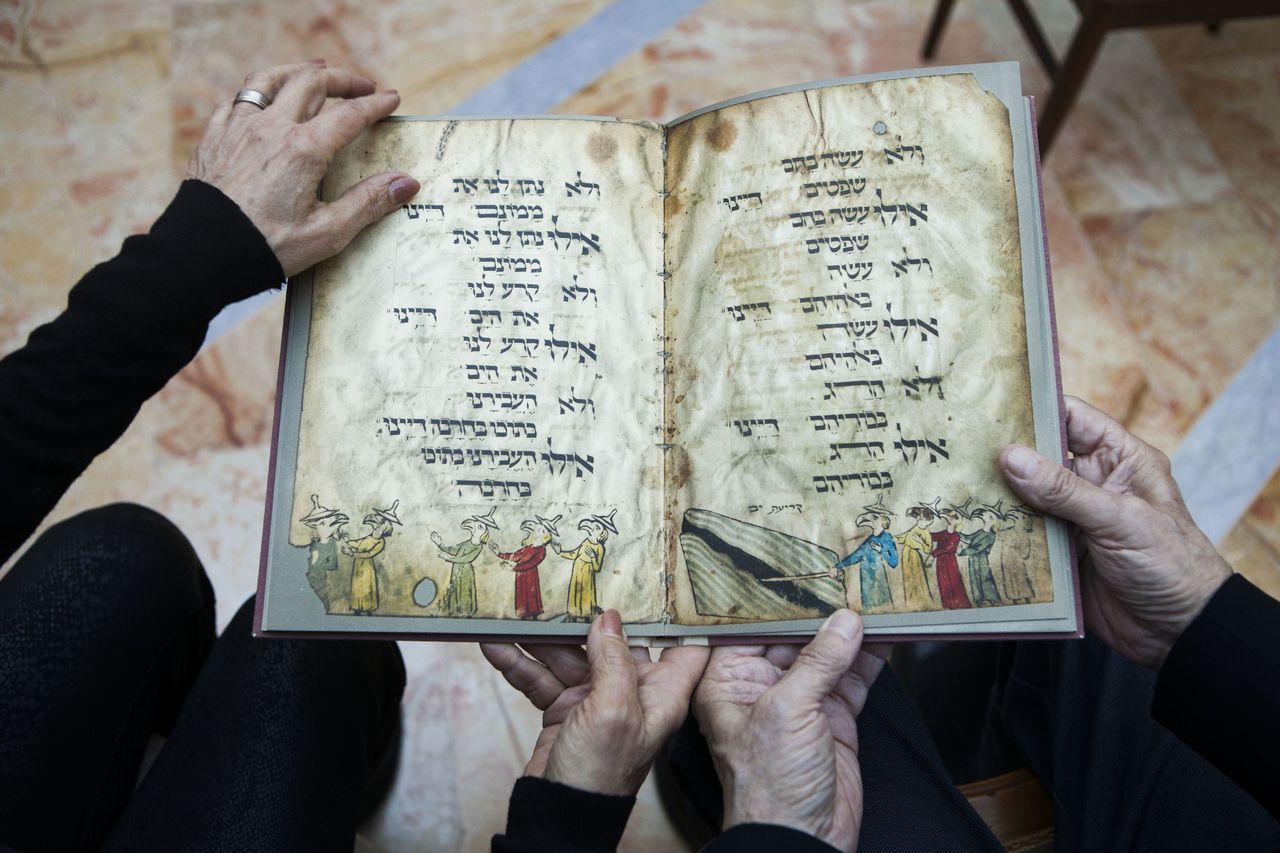 Eli and Shuli Barzilai hold a copy of the Birds’ Head Haggadah in Jerusalem on April 13. Barzilai and his cousins, grandchildren of one of the earliest Jewish victims of the Nazis, are laying claim to a jewel of Israel’s leading museum: the world’s oldest surviving illustrated Passover manuscript. The descendants of a German Jewish lawmaker say the famed Birds’ Head Haggadah, a medieval copy of the text read around Jewish dinner tables on Passover, was stolen from their family during the Nazi era and sold without their consent to the predecessor of the Israel Museum in Jerusalem 70 years ago.