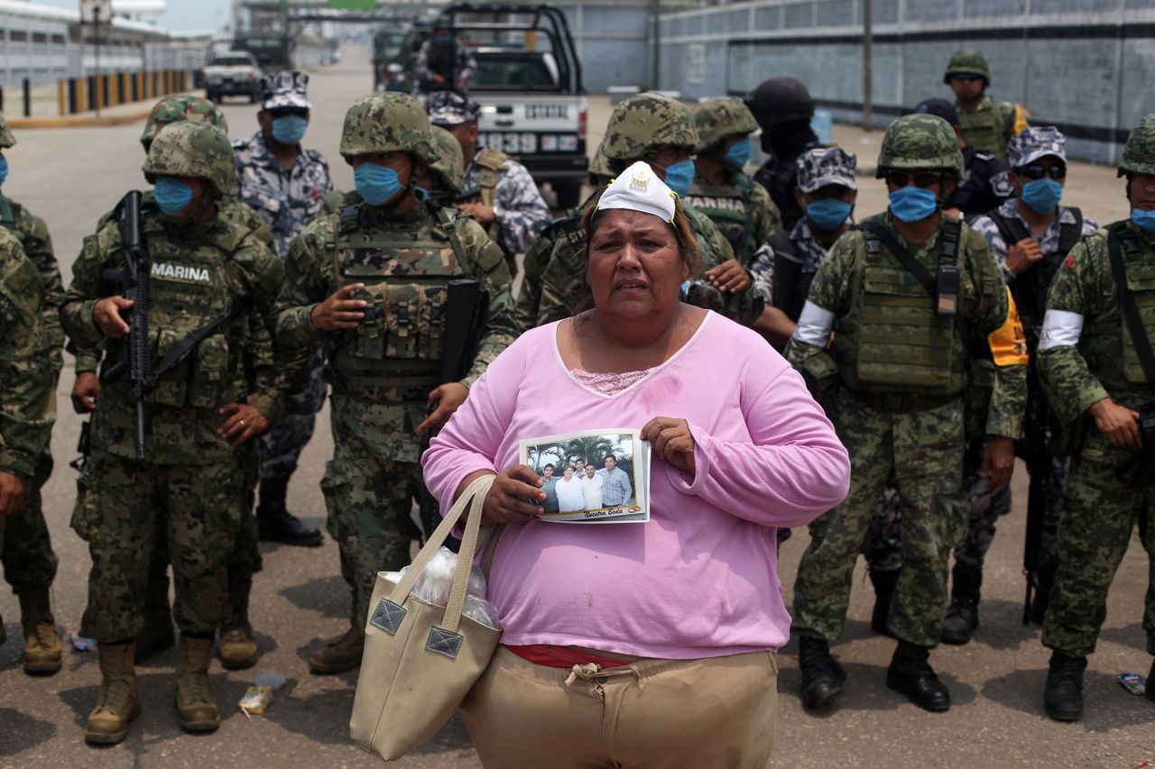 Rosa Villalobos stands in front of army soldiers as she holds up a photo of her son, Luis Alfonso Ruiz, 25, (on the right of the photo), as she tries to get information on his whereabouts outside one of the main entrances to the Pajaritos Petrochemical complex in the city of Coatzacoalcos, Mexico, on Thursday. Ruiz is one of several workers still unaccounted for.