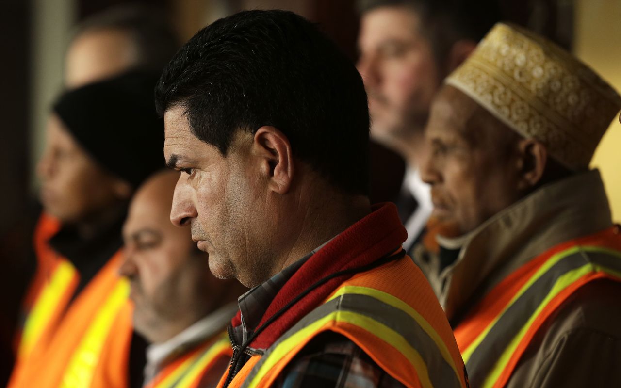 A group of people who work at Seattle-Tacoma International Airport, including Chinderpal Singh (center) listen to questions during a news conference Wednesday in Seattle. More than a dozen workers at Seattle-Tacoma International Airport filed lawsuits on Wednesday over the $15 minimum wage they say they have not been paid.