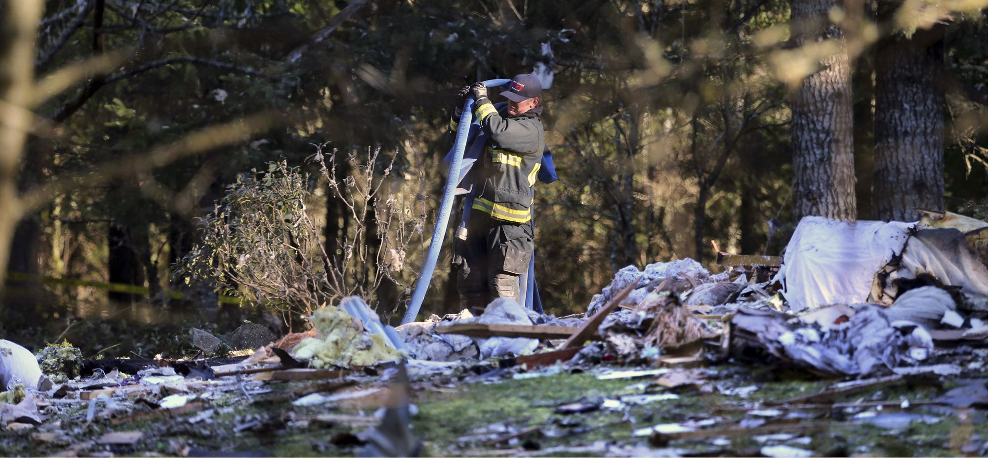 A South Kitsap Fire and Rescue firefighter collects a hose Tuesday at the site of a home explosion in Port Orchard.