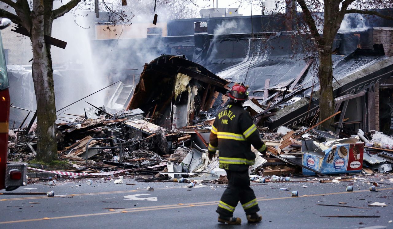 A firefighter walks past smoldering rubble after an early morning explosion Wednesday in Seattle.