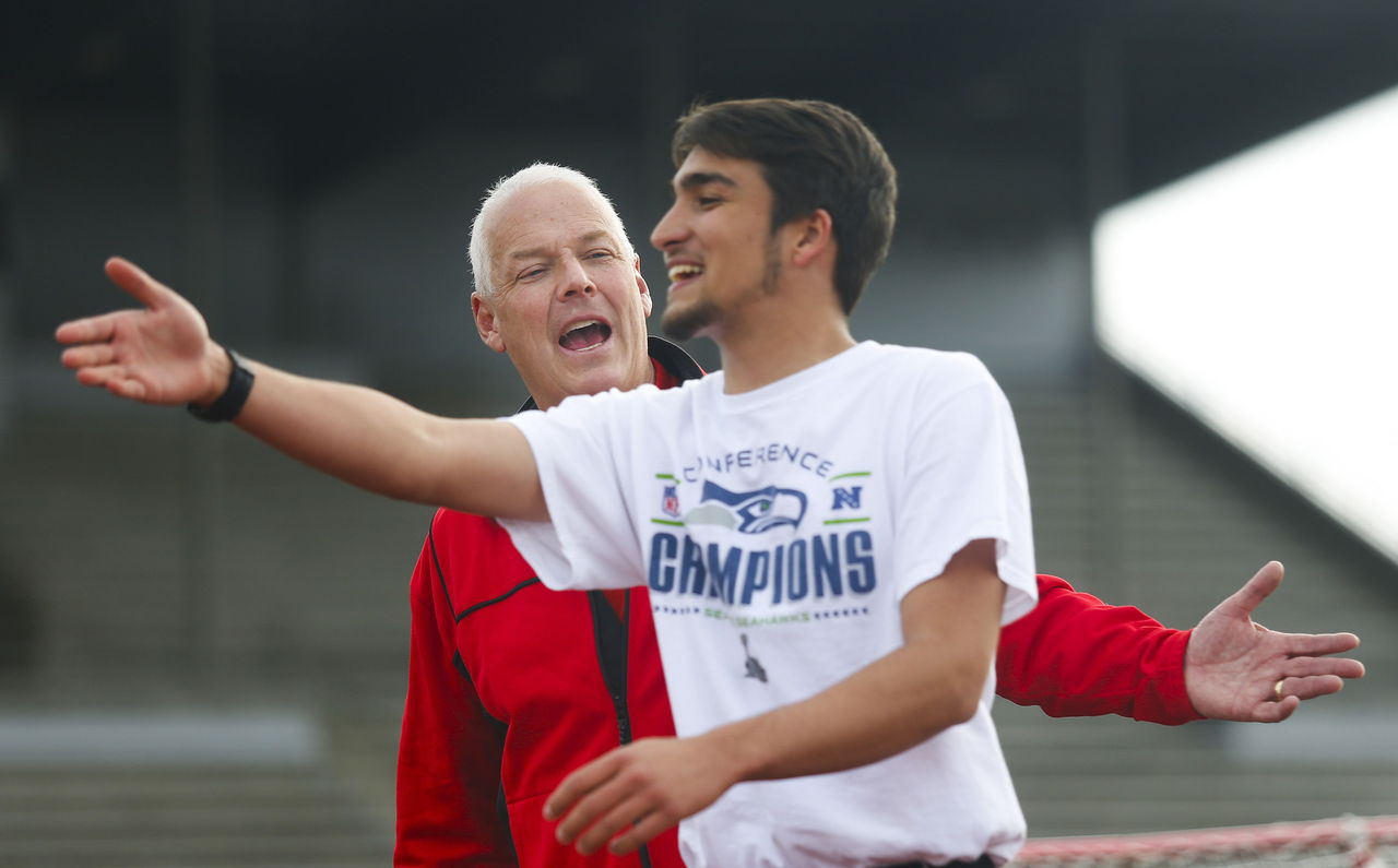 Snohomish High School track coach Tuck Gionet (left) encourages one of his athletes to pick up the pace as the team practice starts in April of 2014.