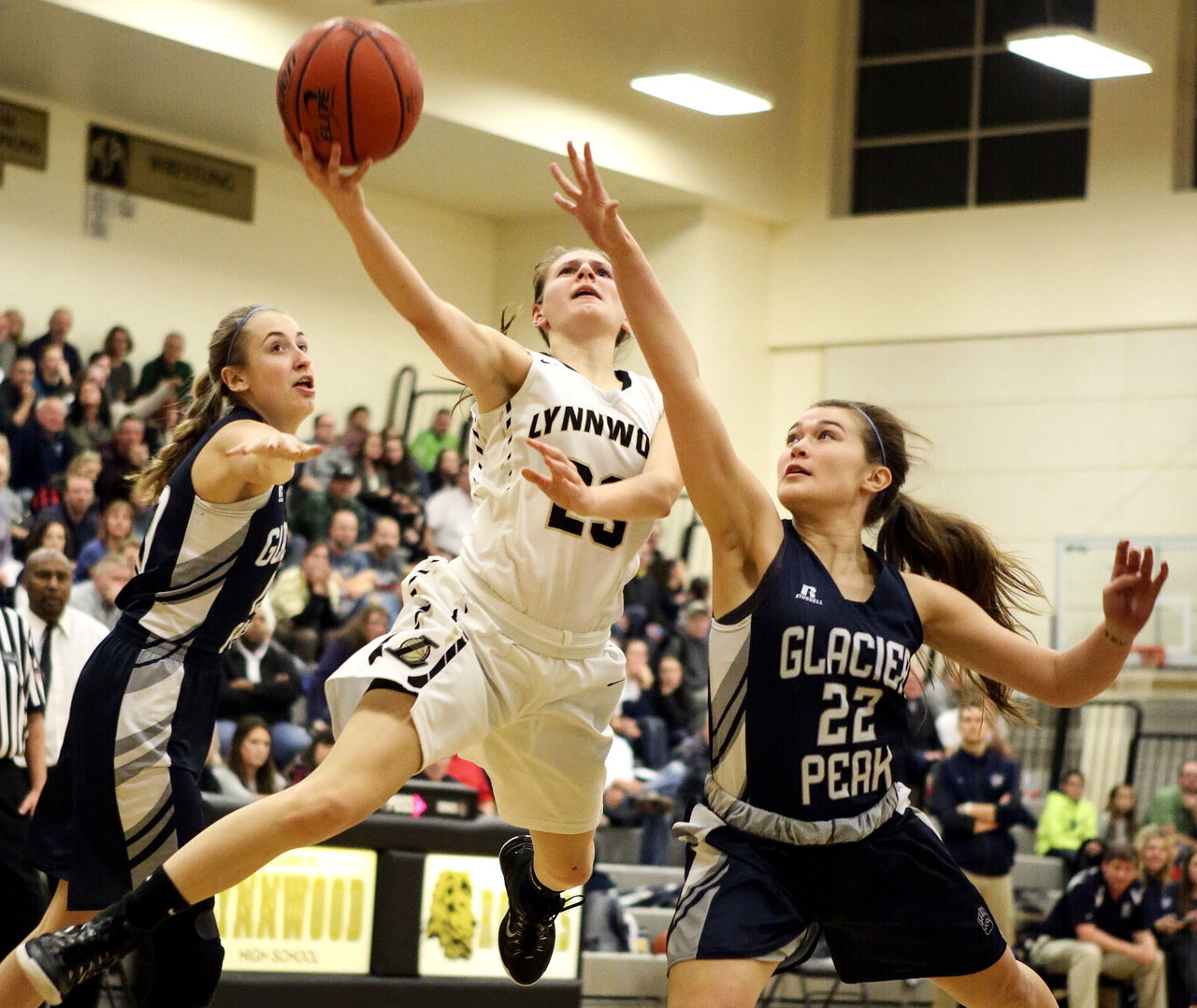 Lynnwood’s Taylor Fahey splits the defense of Glacier Peak’s Lauren Iredale (left) and Sierra Nash during a game Friday night in Lynnwood.