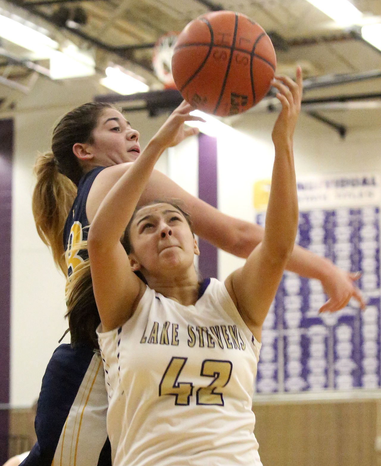 Lake Stevens’ Rocky Leenstra attempts to pull in a rebound with Mariner’s Hannah Hezekiah trailing Thursday night in Lake Stevens.