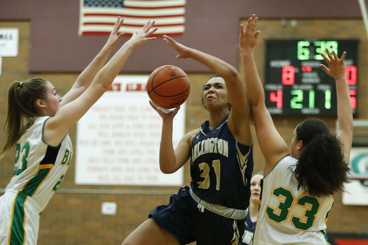 Arlington’s Jayla Russ (31) drives through Bishop Blanchet’s Lee Erickson (23) and Jillese Bush (33) during a 3A state regional game on Saturday at Mountlake Terrace High School.
