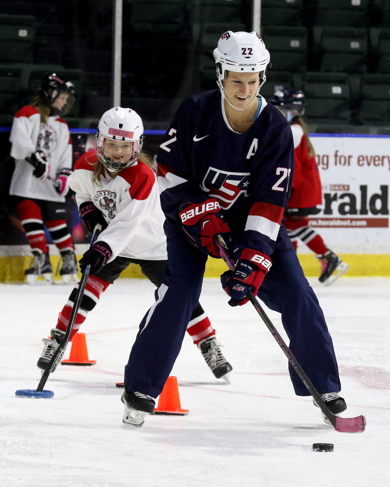 The U.S. women’s hockey team’s Kacey Bellamy shows stick skills to a player as the team works out with local youth girls teams at Xfinity Arena on Monday.