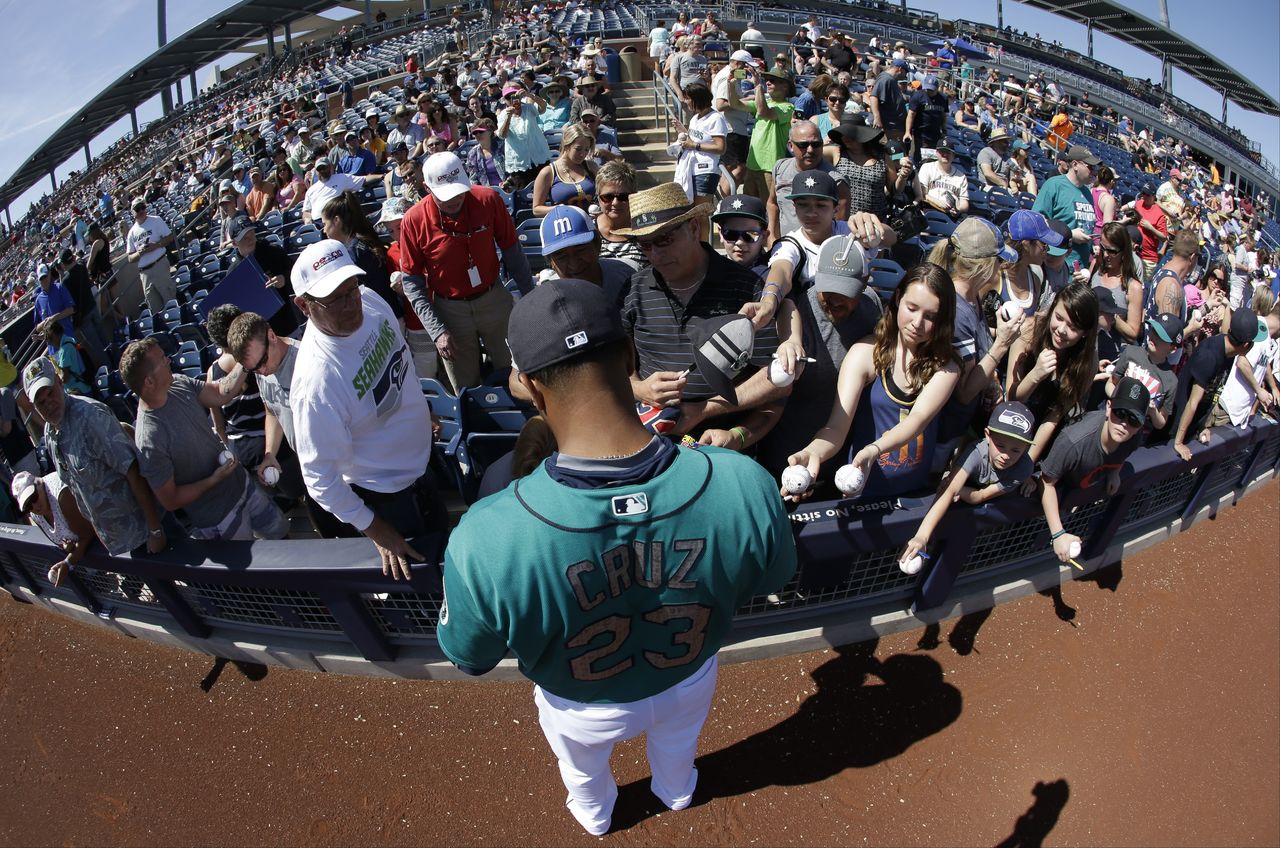 The Mariners’ Nelson Cruz signs autographs before a spring training game against the Reds on March 13 in Peoria, Ariz.
