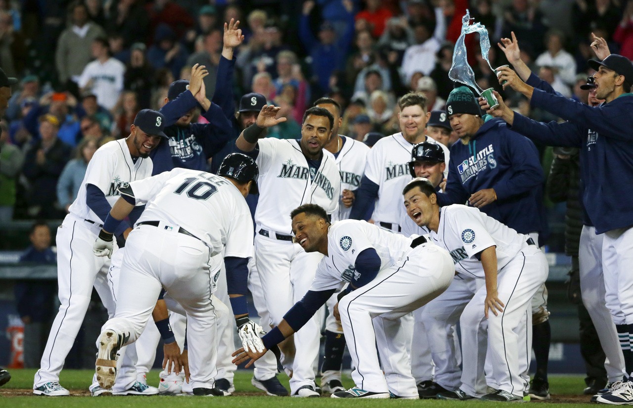 The Mariners’ Dae-Ho Lee (10) is greeted at home plate by his Seattle teammates after he hit a walk-off two-run home run in the bottom of the tenth inning to lift the M’s to a 4-2 win over the Rangers.
