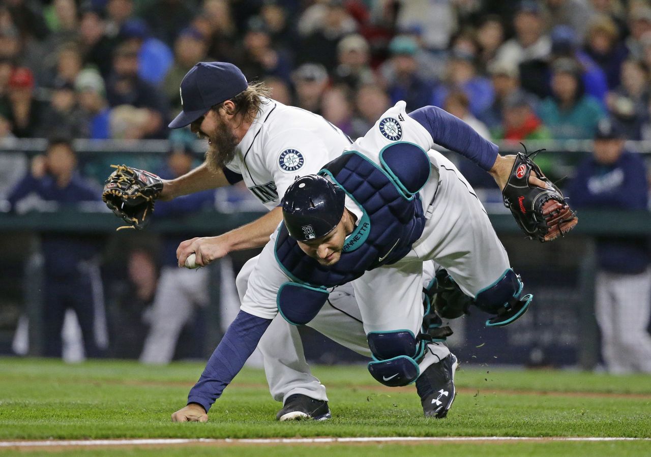 Mariners starting pitcher Wade Miley collides with catcher Chris Iannetta as they try to field a bunt single by the Rangers’ Delino DeShields during the third inning of Tuesday’s game.
