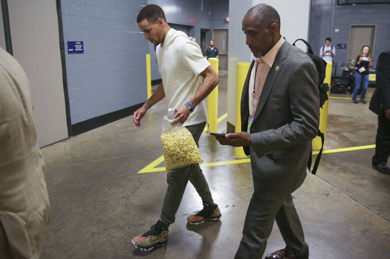 Golden State guard Stephen Curry carries popcorn as he limps out of the Toyota Center in Houston on Sunday following Game 4 of the Warriors’ playoff series against Houston. The Warriors announced Monday that Curry will miss at least two weeks with a sprained knee.