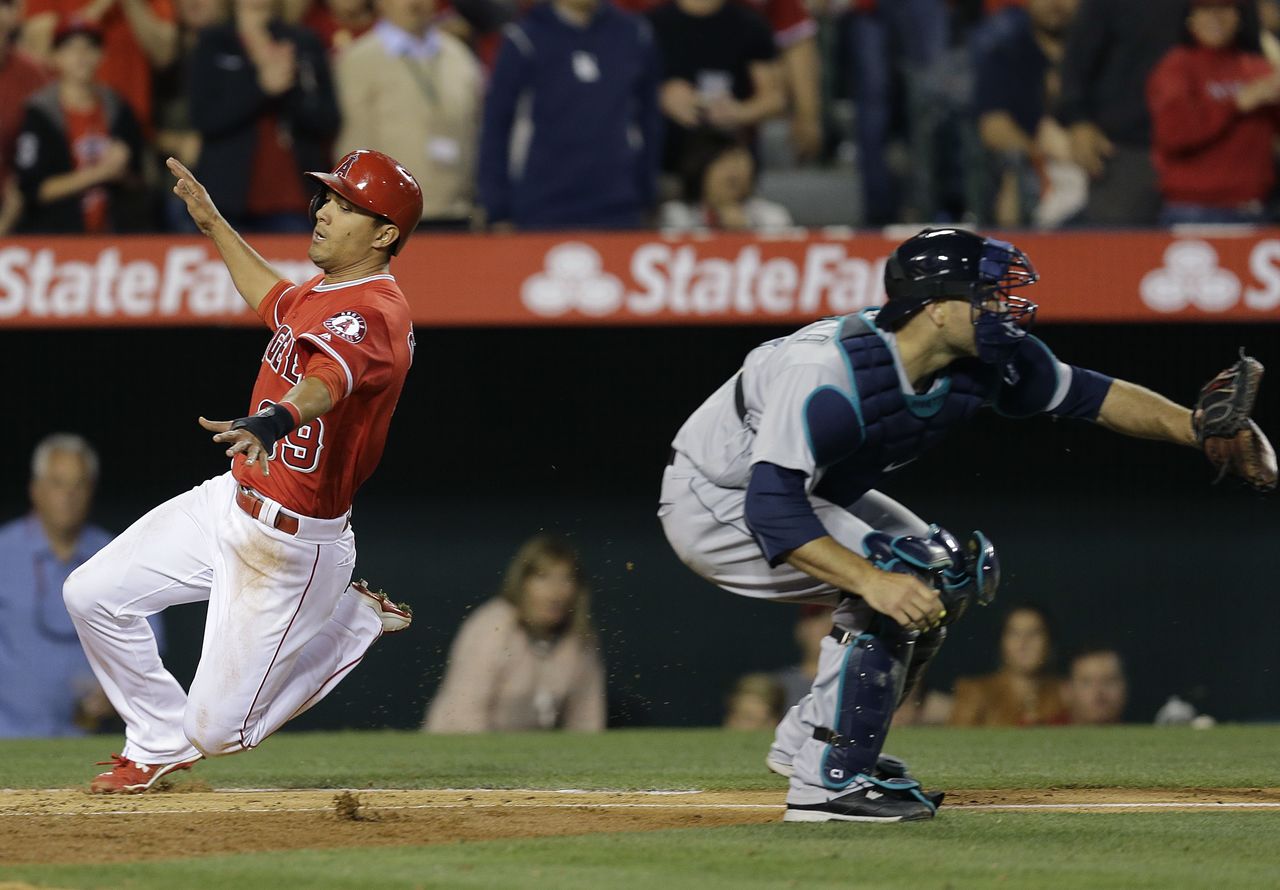 The Angels’ Rafael Ortega scores as Mariners catcher Chris Iannetta reaches for the throw in the eighth inning of Saturday’s game.