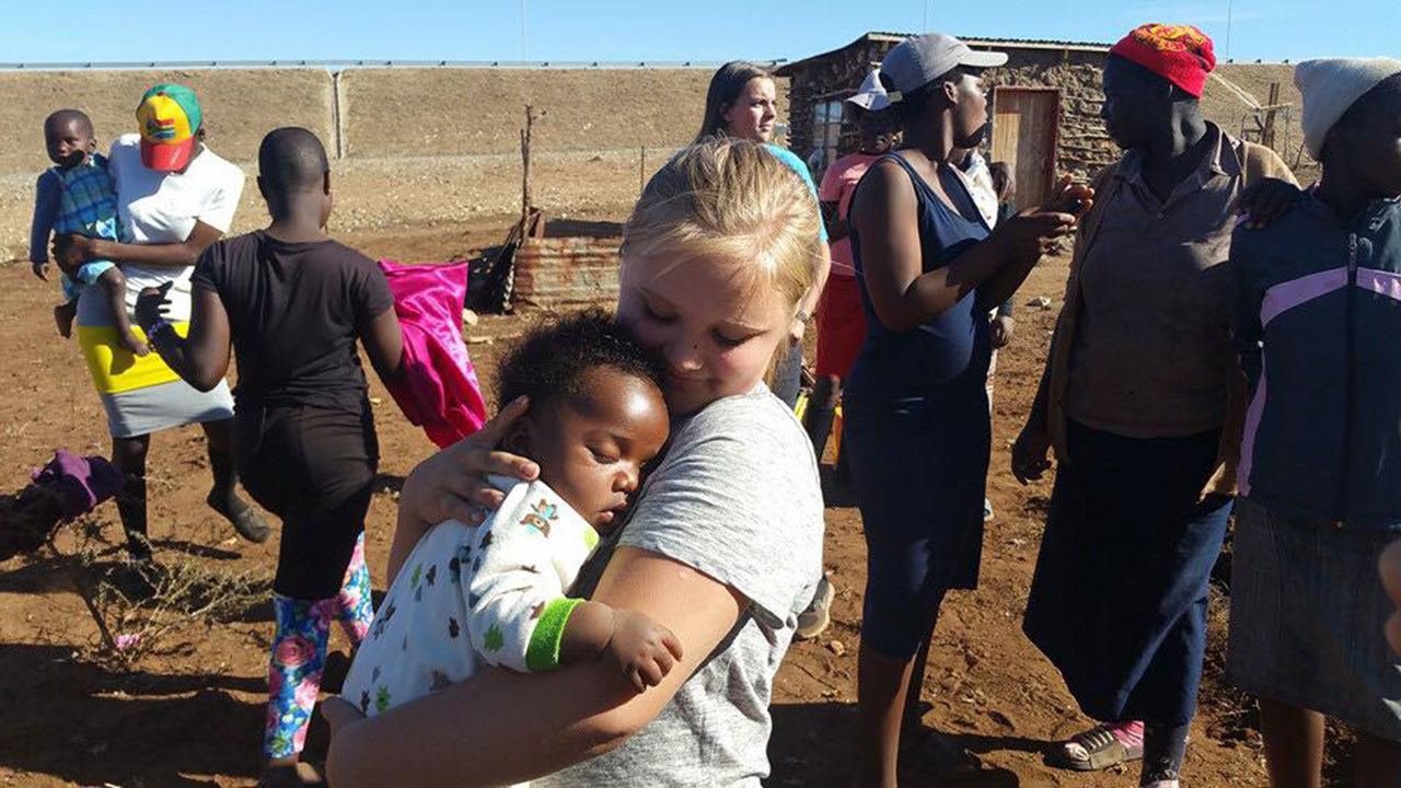 Kennedy King holds a baby on a homestead in the rural community of Mbalenhle, in Swaziland, during a mission trip Aug. 7-17, with several other youth from Bethany Christian Assembly of Everett. The teens helped missionary Stan Drew with a variety of projects. On that day, girls on the missions team helped the family plant a garden and the boys dug a pit latrine. (Contributed photo)