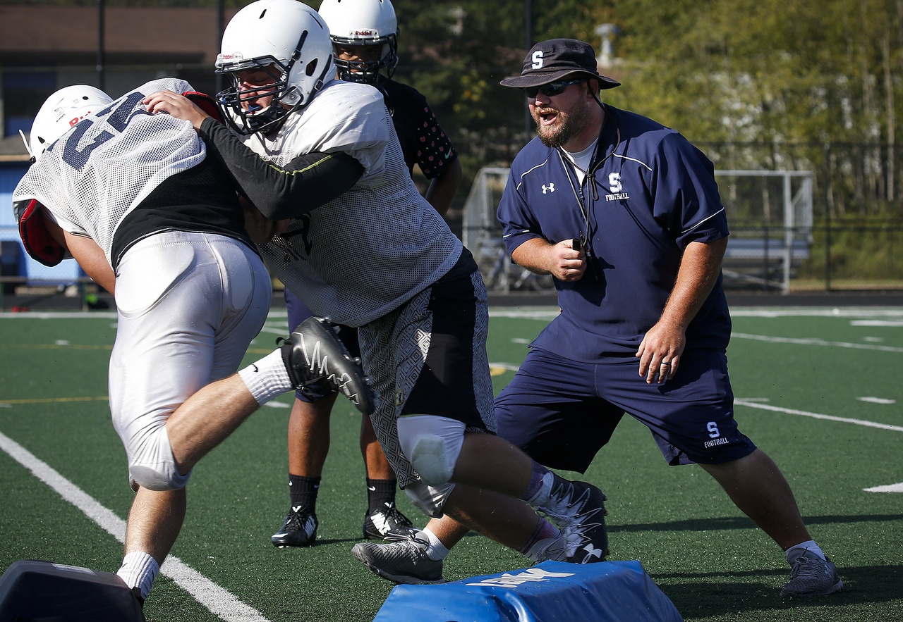 Sultan High School football head coach Jim Kruckenberg (right) works on a tackling drill with players during a practice on Aug. 26. (Ian Terry / The Herald)