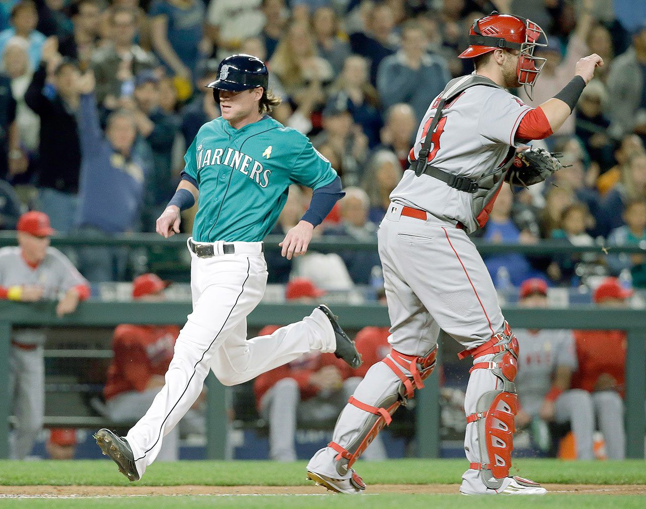 Seattle’s Ben Gamel (left), scores in the first inning of his Mariners’ debut as Los Angeles Angels catcher Jett Bandy waits for the ball on Friday night in Seattle. Gamel just joined the team after a trade with the Yankees. (AP Photo/Elaine Thompson)