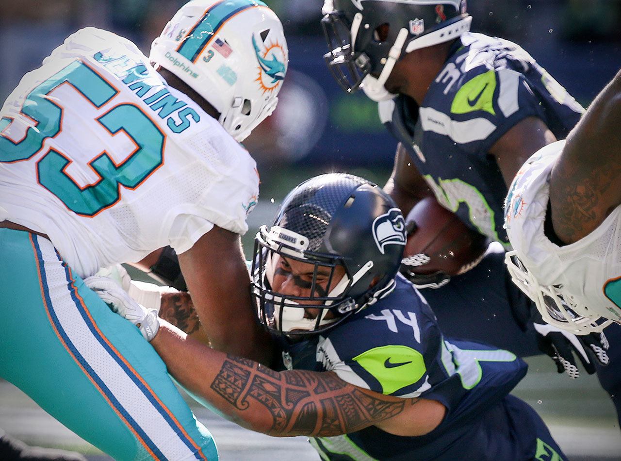 Seahawks fullback Taniela Tupou (44), an Archbishop Murphy alum, blocks Dolphins linebacker Jelani Jenkins to make room for running back Christine Michael (32) during a game Sunday at CenturyLink Field in Seattle. (Kevin Clark / The Herald)