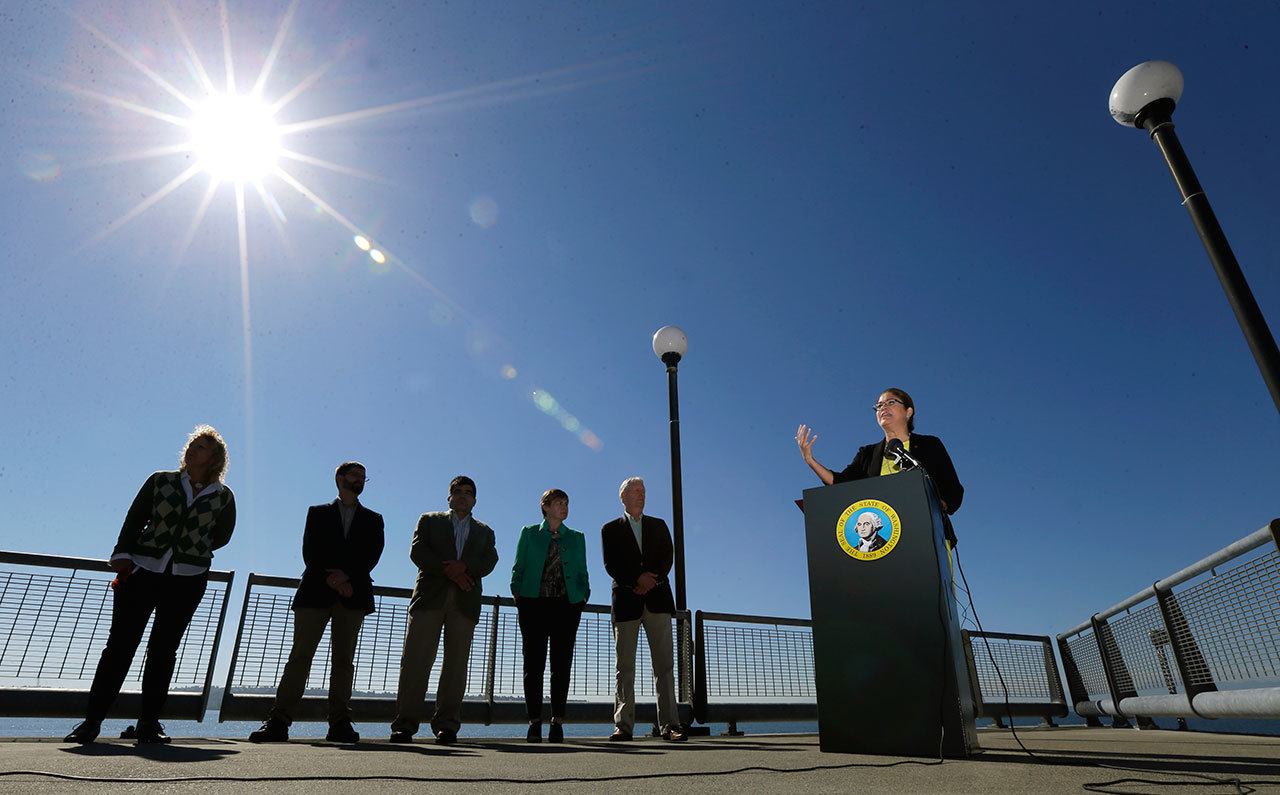 Maia Bellon (right) director of the Washington State Deptartment of Ecology, speaks at a press conference, Thursday, overlooking Elliott Bay in Seattle. Washington state environmental regulators finalized a new rule Thursday to limit greenhouse gas emissions from large polluters. (AP Photo / Ted S. Warren)