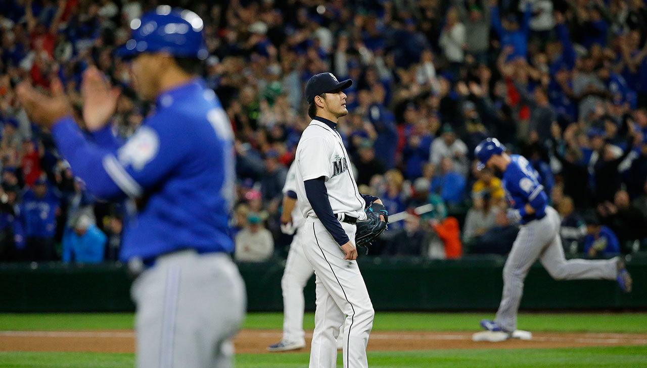 Mariners starting pitcher Hisashi Iwakuma (center) stands on the mound as the Blue Jays’ Michael Saunders (right) rounds the bases after hitting a two-run home run in the fourth inning of a game Tuesday in Seattle. (AP Photo/Ted S. Warren)