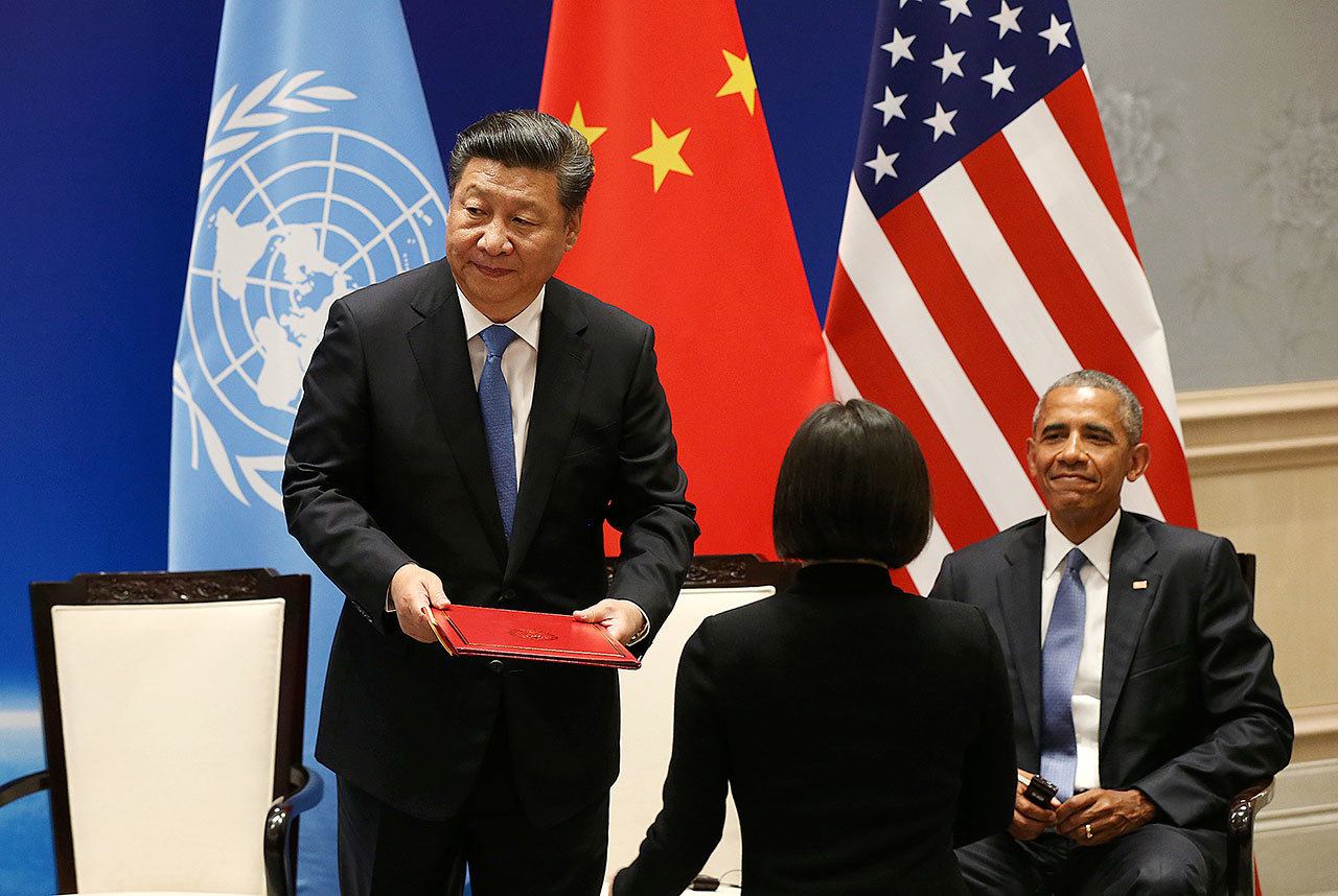 Chinese President Xi Jinping stands up to hand over documents for the ratification of the Paris climate change agreement as U.S. President Barack Obama looks on in Hangzhou, China, on Saturday. (How Hwee Young / Associated Press)