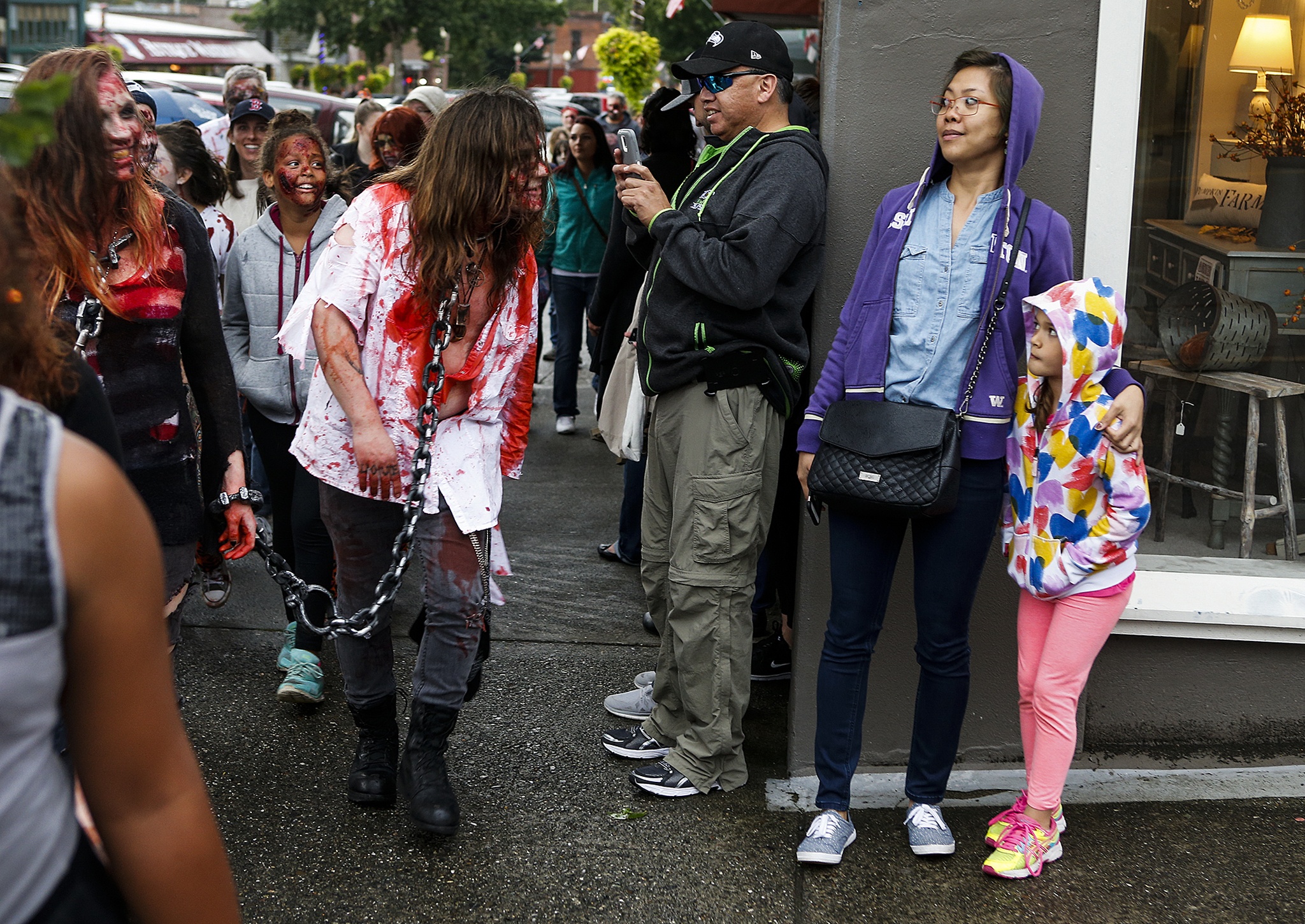 Leica Batingan (center right) and Karmin Kasberg (right), 8, of Seattle, shy away from an encroaching zombie during the third annual Snohomish Zombie Walk on Saturday evening. Participants in the walk brought donations for the Snohomish Food Bank before setting off down 1st Street to scare and have fun with unsuspecting bystanders. (Ian Terry / The Herald)