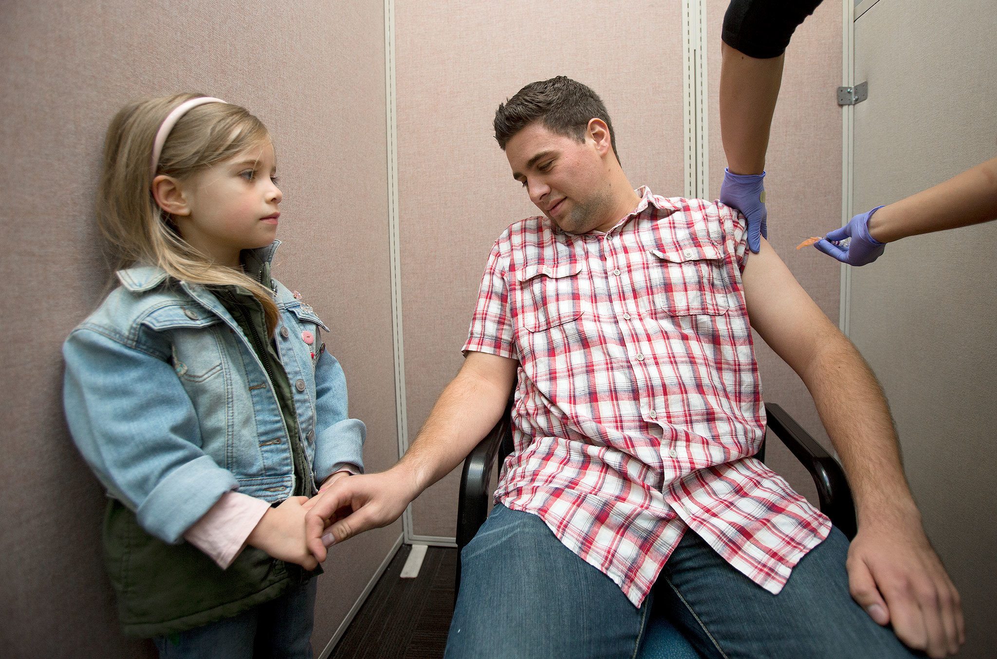 Parker Castano, who admits a fear of needles, has his hand held by his niece, Adeline, 4, as he gets a flu shot at the Everett Clinic on Thursday in Everett. (Andy Bronson / The Herald)