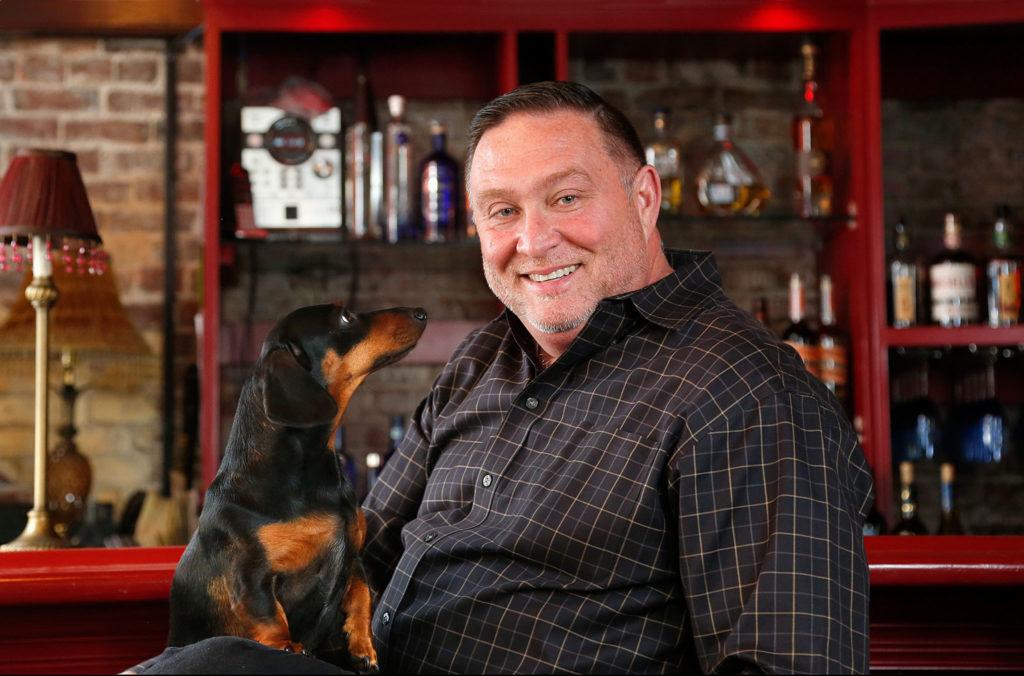 Brenton Holland, sits with his dog, Sophie, at the bar of his recently acquired Prohibition Grille & Saloon restaurant. (Dan Bates / The Herald)
