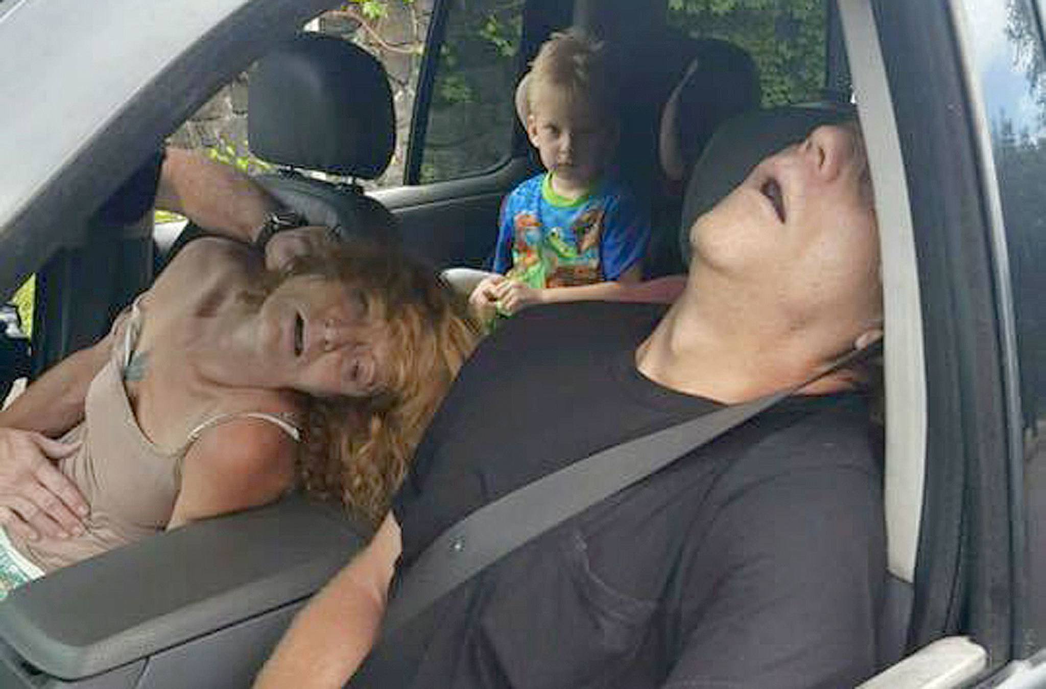 A child sits in a vehicle behind his mother and a man, both of whom are unconscious from a drug overdose in East Liverpool, Ohio, on Wednesday. (East Liverpool Police Department)