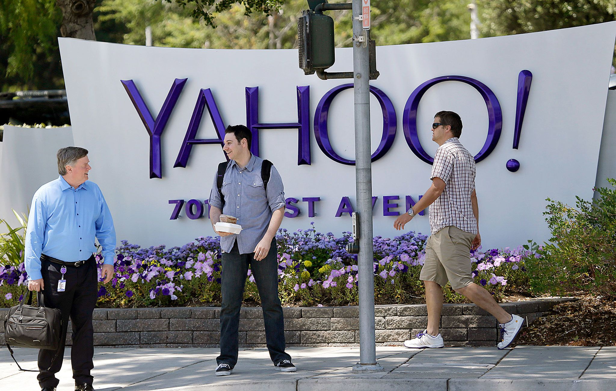 People walk in front of a Yahoo sign at the company’s headquarters in Sunnyvale, California, in 2014. (AP Photo/Marcio Jose Sanchez)