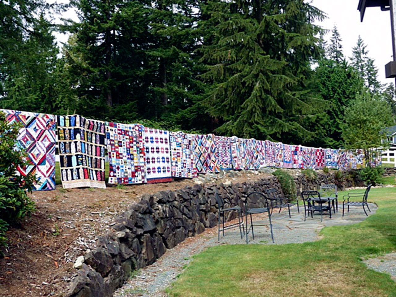Chelsey Weber, an employee of Quilting Mayhem in Snohomish, organized a team of employees and customers to make quilts for each of the 20 veterans who live at Sebastian House. Before delivery, the quilts were displayed on a fence to be photographed. (Contributed photo)