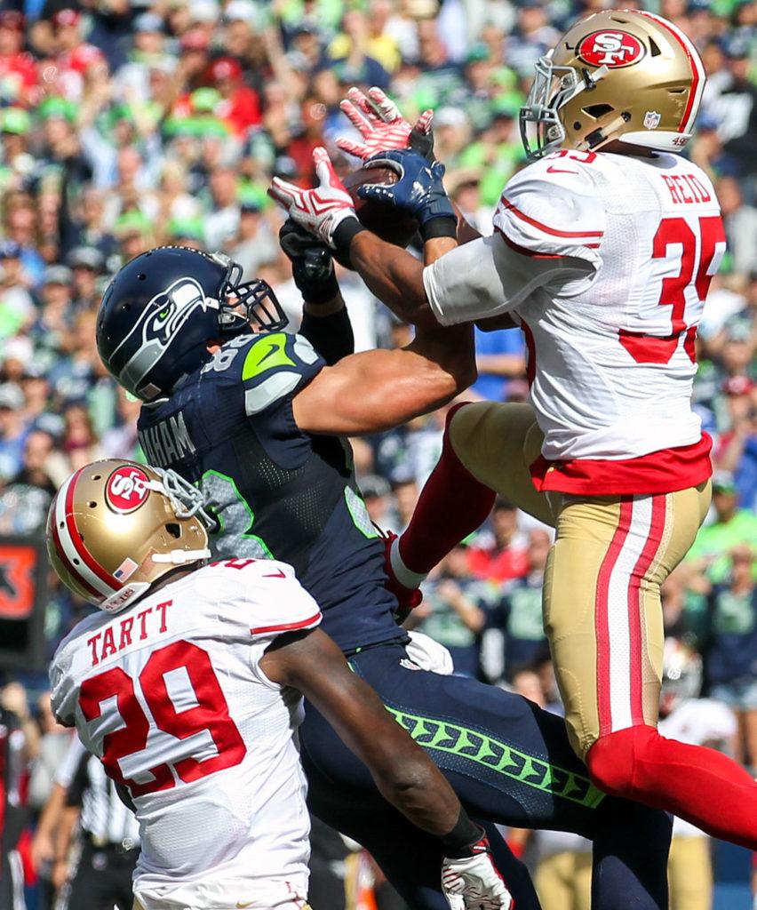 Seahawks tight end Jimmy Graham muscles in a reception with 49ers safety Jaquiski Tartt, left, and 49ers safety Eric Reid defending Sunday afternoon at Century Link Field in Seattle on September 25, 2016. The Seahawks are 2-1 after defeating the 49ers 37-18. (Kevin Clark / The Herald)

