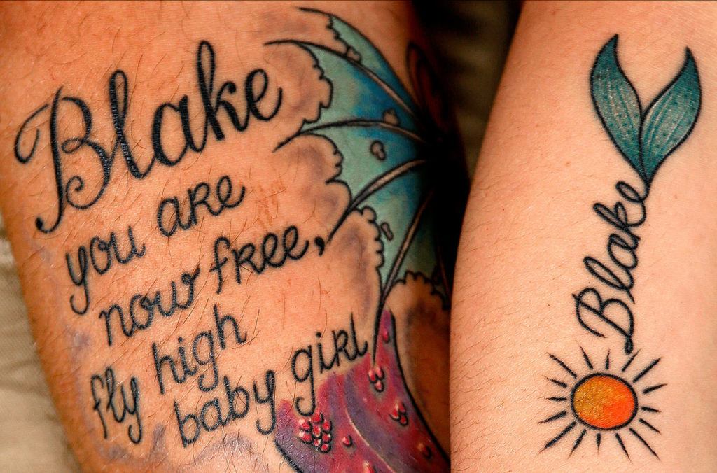 Jeff and Stephanie Reid got tattoos a few days after their daughter died. The sun on Stephanie’s arm is about Blake being their sunshine. The butterfly on Jeff’s arm represents the transformation that Blake has made, a kind of metamorphosis. The fins on Stephanie’s arm are a mermaid tail. Blake loved being in water, Stephanie said. Out of water, she couldn’t move her legs, but in water she could, and she loved it. (Dan Bates / The Herald)
