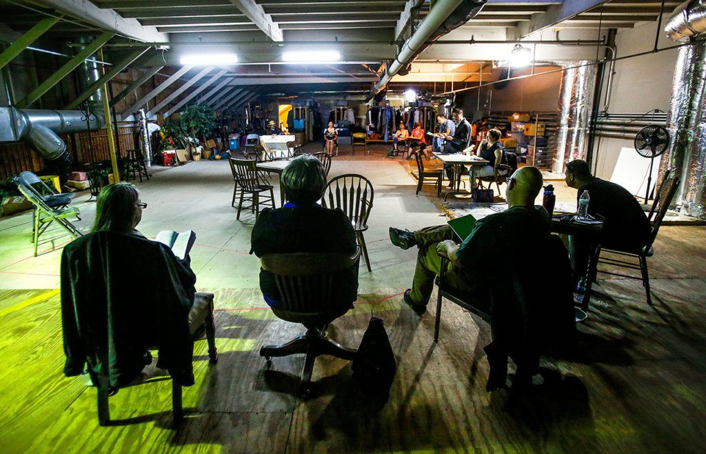 In their newly acquired home theater space in Marysville, Red Curtain staff and cast meet and talk before rehearsing part one in a production of “Arsenic and Old Lace.” Director David Bailey can be seen sitting on the end of a table midway on right. Actor Justin Dabney is sitting just beyond Bailey. (Dan Bates / The Herald)

