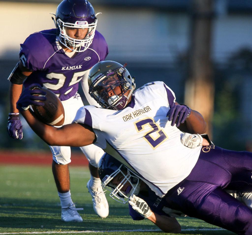 Oak Harbor’s Princeton Lollar Jr. stretches outs for additional yardage with Kamiak’s Raul Zarate looking on during a game Thursday night at Goddard Stadium in Everett. (Kevin Clark / The Herald)
