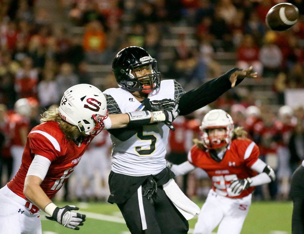 Lynnwood’s Alton Hammond attempts a pass with Snohomish’s Jess Harris (left) and Tyler Massena (right) closing during a game Friday night at Veterans Memorial Stadium. (Kevin Clark / The Herald)
