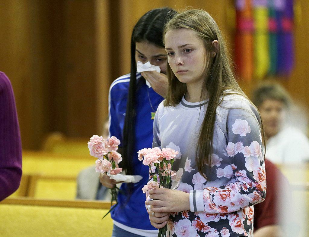 Rachel Marsh, 15, right, and Selena Orozco, 15, left, carry flowers as they attend a prayer service Saturday at the Central United Methodist Church in Sedro-Woolley. The service was held in regard to Friday’s fatal shooting of several people at a Macy’s department store at the Cascade Mall in nearby Burlington. Both girls said they knew one of the victims of the shooting. (AP Photo/Ted S. Warren)
